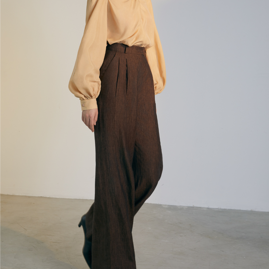 The side of a model wearing brown colored loose Pants